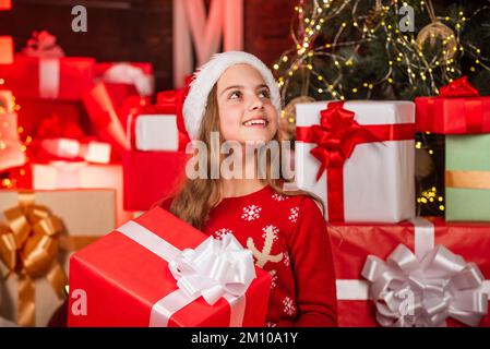 Buon Natale. Felice concetto di infanzia. Scopri la bellezza dell'inverno. Scatole regalo di natale del cappello di santa del capretto. Babbo Natale mi ha portato dei regali. Negozio di articoli da regalo. Bambino Foto Stock