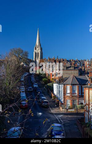 Guardando sopra la collina di muswell da alto.A guglia della chiesa contro un cielo blu profondo così come molti tetti e camini di case terrazzate.Many auto parcheggiate Foto Stock