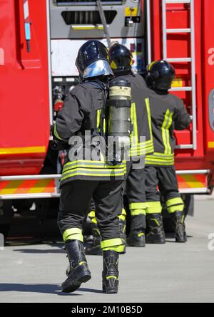 pompieri con serbatoio di ossigeno e camion antincendio in background durante un'emergenza Foto Stock