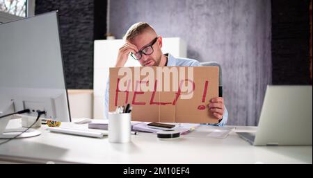 Giovane uomo stressato alla scrivania in ufficio Foto Stock