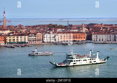 Paesaggio urbano, vista degli uccelli di Venezia e della laguna marina con vaporetto e traghetto in primo piano. Immagine panoramica dai colori arancione e blu. Foto Stock