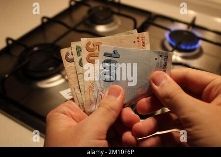 mano uomo che conta soldi. stufa a gas in background. costi elevati del gas e dell'elettricità, crisi economica. Foto Stock