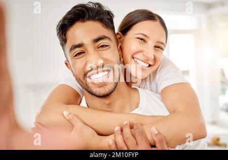 Felice innamorato di te. una giovane coppia in piedi insieme e prendere un selfie a casa. Foto Stock