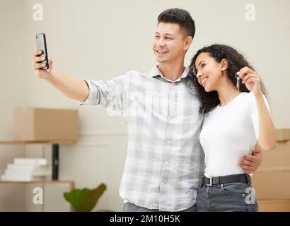 Eccitati per il nostro viaggio insieme. una giovane coppia che prende un selfie nella loro nuova casa. Foto Stock