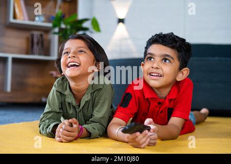 Felice sorrido teeanger fratelli guardando la tv o la televisione mentre si posa sul pavimento a casa - concetto di enternatimnnet, legame e vacanze fine settimana Foto Stock