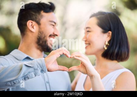Grazie per avermi amato come te. una giovane coppia felice che fa un gesto a forma di cuore in un giardino. Foto Stock