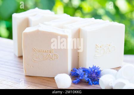 Sapone bianco fatto a mano con fiori blu e bozzoli di seta su sfondo verde Foto Stock