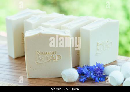 Sapone bianco fatto a mano con fiori blu e bozzoli di seta su sfondo verde Foto Stock