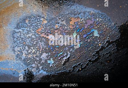 Macchie di olio o benzina sono sparse casualmente sull'asfalto dopo la pioggia. Foto Stock