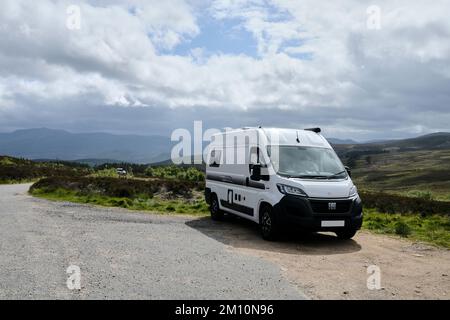 Vista frontale di tre quarti del camper parcheggiato lungo la strada che si affaccia sul paesaggio nei Cairngorms Foto Stock