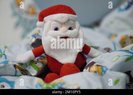 Un giocattolo di peluche Babbo Natale del marchio Milka seduto su un lenzuolo. Foto Stock