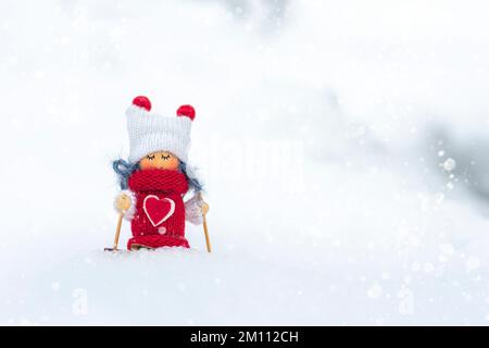 Ragazza sciatore giocattolo in sciarpa e cappello lavorato sciare Elf giocattolo sugli sci in paesaggio innevato Capodanno, buon Natale biglietto d'auguri inverno felice anno nuovo Ciao dicembre, gennaio, febbraio. Foto Stock