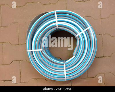 Irrigazione giardino tubo ritorto su piastrella. Tubo di irrigazione in gomma attorcigliato, vista dall'alto. Foto Stock