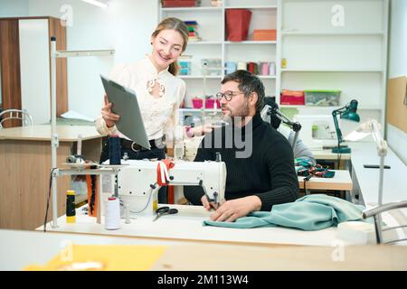 Donna con un tablet è in piedi sul posto di lavoro del sarto Foto Stock