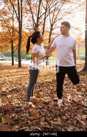 La giovane donna sta facendo il riscaldamento con la sua amica nel parco Foto Stock