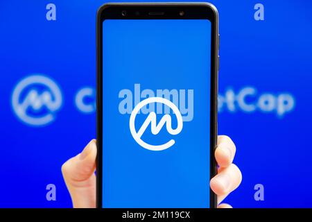Ucraina, Odessa - Ottobre, 9 2021: Tenere la mano mobile con l'app CoinMarketCap in esecuzione sullo schermo dello smartphone con il logo CMC sullo sfondo. L'autorità per i dati di criptovaluta più affidabile al mondo Foto Stock