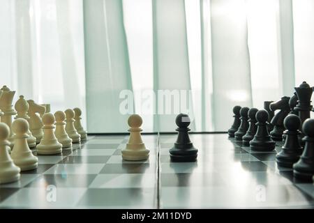 Scacchiera con confronto pedine bianche e nere. Vista laterale con prospettiva e spazio di copia Foto Stock