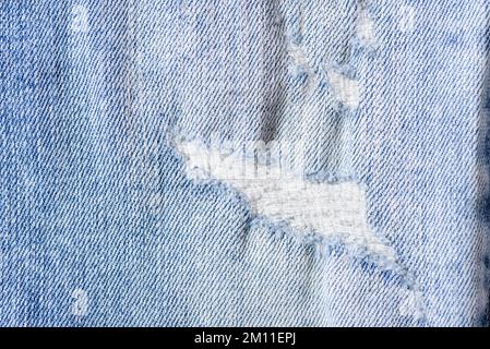 Primo piano di un colore blu e strappato jeans texture sfondo. Foto Stock