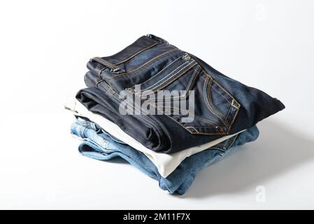 Un mucchio di jeans su sfondo bianco. Foto Stock