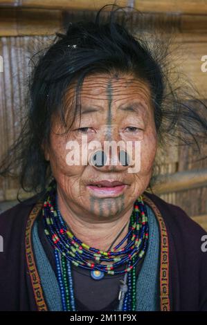 Ziro, Arunachal Pradesh, India - 11 13 2010 : Ritratto della vecchia donna tribale di Apatani con tatuaggio facciale e tappi per il naso che indossano la collana tradizionale Foto Stock