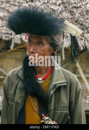 Raga, Arunachal Pradesh, India - 11 14 2010 : Ritratto dello sciamano della tribù di Nyishi che indossa un coltello da machete e un copricapo tradizionale con piume e pelliccia Foto Stock