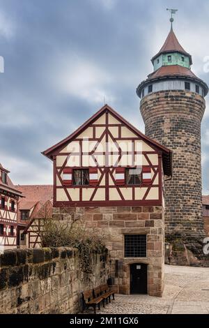 Edificio a graticcio nel cortile del Castello Imperiale e la Torre Sinwell sullo sfondo. Norimberga, Baviera, Germania. Foto Stock