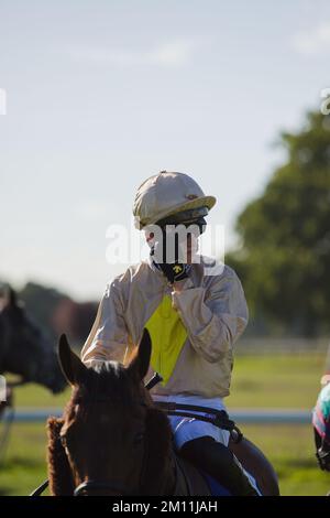 Il jockey Oisin McSweeney aspetta di essere condotto nelle porte di partenza alle corse di York. Foto Stock