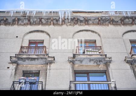 Grandi ghiaccioli appesi sul tetto della casa in inverno Foto Stock