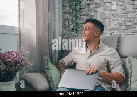 Il giovane ha finito il lavoro e lo studio pronto a rilassarsi a casa da solo sul divano godendosi del tempo libero divertendosi. Concetto disconnesso e stile di vita di salute mentale Foto Stock