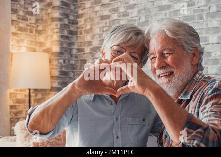 Primo piano delle mani di due nonni maturi che fanno una forma di cuore con le loro dita insieme. Sorridendo e divertendosi nella gente d'amore. Foto Stock