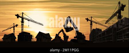 Cantiere con gru, escavatori, case e nuovi edifici silhouette Foto Stock