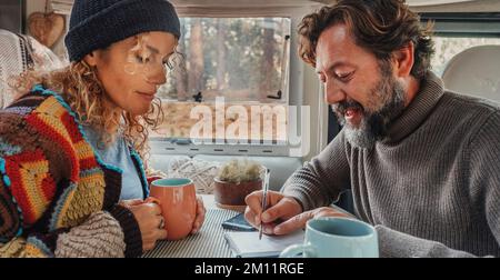 La coppia pianifica la destinazione di viaggio dall'interno di un camper. Uomo e donna attività di svago al coperto insieme in moderno casa motore interni. Concetto di vanlife e vivere fuori rete per persone alternative Foto Stock