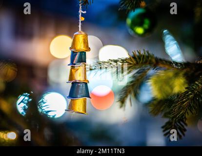 09 dicembre 2022, Hessen, Francoforte sul meno: Capsule di caffè vuote in alluminio, infilate su una corda, appese come decorazioni di alberi di Natale su un albero di Natale nel quartiere di Bornheim. Foto: Frank Rumpenhorst/dpa Foto Stock