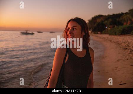 Una giovane donna che si gode le luci spettacolari durante il tramonto in una delle spiagge dell'isola mauritius, in Africa Foto Stock