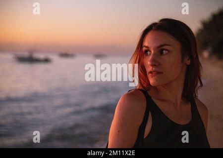 Una giovane donna che si gode le luci spettacolari durante il tramonto in una delle spiagge dell'isola mauritius, in Africa Foto Stock