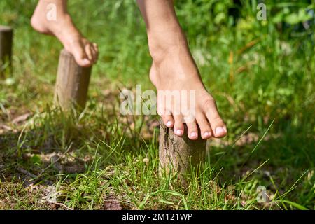 Camminare a piedi nudi - piedi equilibrando su pioli di legno, primo piano Foto Stock