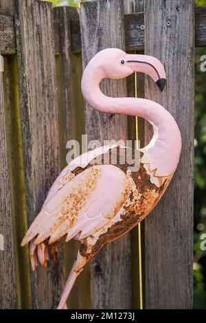 Scultura in giù di un fenicottero si appoggia contro la recinzione del giardino Foto Stock