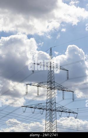 Parte superiore del pilone elettrico contro il cielo blu con le nuvole di pioggia in Germania Foto Stock