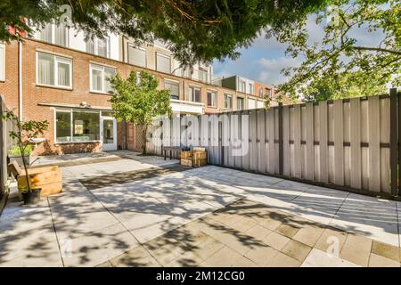 un cortile sul retro con una recinzione e alcune piante in vaso sul terreno di fronte ad un condominio Foto Stock