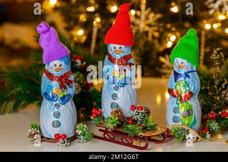 Di fronte all'albero di Natale si trovano le nevi al cioccolato al latte con una slitta. Foto Stock