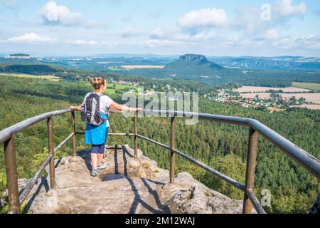 Donna anziana che fa escursioni sulle montagne di arenaria dell'Elba con vista sul Papststein in estate, la Svizzera sassone. Foto Stock