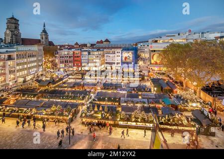 Panorama del mercato di Natale a Stoccarda sulla piazza del municipio, vista dalla finestra panoramica del municipio alle bancarelle, la fila di negozi, la chiesa collegiata e il grande magazzino Breuninger Foto Stock