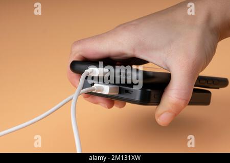 collegamento dell'accumulatore del power bank portatile usb e del telefono di colore nero in mano. Foto Stock