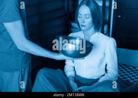 Uomo con ciotole tibetane in terapia sonora nel centro termale Foto Stock