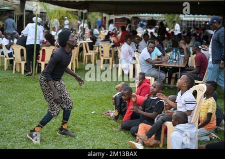 KENYA, Nairobi, classe media in birreria all'aperto, spettacolo acrobatico / KENIA, Nairobi, Mittelklasse im Biergarten, akrobatische Vorführung zur Unterhaltung der Gäste Foto Stock