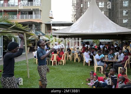 KENYA, Nairobi, classe media in birreria all'aperto, spettacolo acrobatico / KENIA, Nairobi, Mittelklasse im Biergarten, akrobatische Vorführung zur Unterhaltung der Gäste Foto Stock