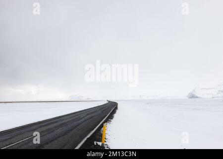 Strada che conduce attraverso il paesaggio innevato ghiacciato dell'Islanda meridionale in inverno Foto Stock