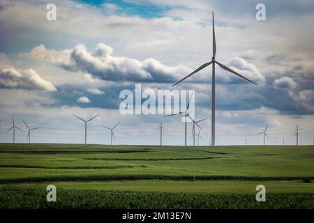 Le turbine eoliche si trovano nei campi di grano e le nuvole di tempesta all'orizzonte vicino a Stuart, Iowa. Foto Stock