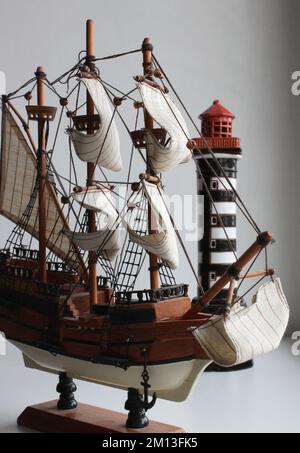 Miniatura di imbarcazione a vela in legno su Uno stand modello con faro isolato foto d'archivio Foto Stock
