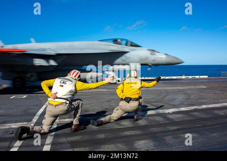 221207-N-MU675-1043 OCEANO PACIFICO (7 dicembre 2022) Capo di comando Joel Rodriguez, a sinistra, da Woodland, Calif., e Lt. CMdR. Andrew Castro, di Knoxville, Tenn., e, segnale a F/A-18E Super Hornet, assegnato a Strike Fighter Squadron (VFA) 14, per lanciare dal ponte di volo della portaerei di classe Nimitz USS Abraham Lincoln (CVN 72). Abraham Lincoln sta conducendo le operazioni di routine nella flotta degli Stati Uniti 3rd. (STATI UNITI Foto Navy di Mass Communication Specialist 3rd Classe Han Puyu) Foto Stock